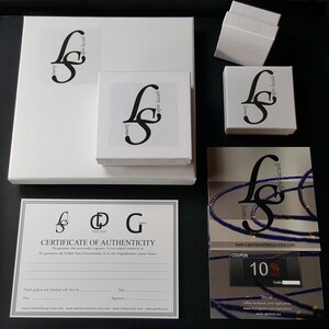 May include: A white box with a black logo that says "Gemory Design" and "Samo" on it. The box is sitting on a white surface. There is a certificate of authenticity with the same logo and the text "Certificate of Authenticity" on it. There is also a coupon with the text "10% Save" on it.