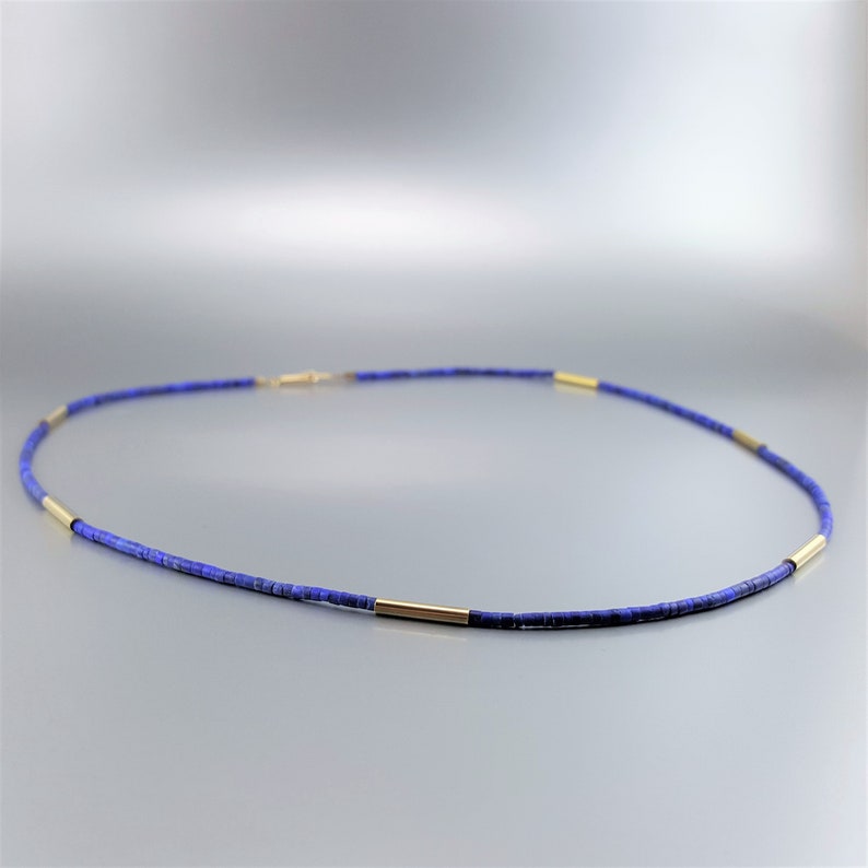 May include: A delicate necklace made of small, dark blue lapis lazuli beads interspersed with gold spacers. The necklace is approximately 18 inches long and has a lobster claw clasp.