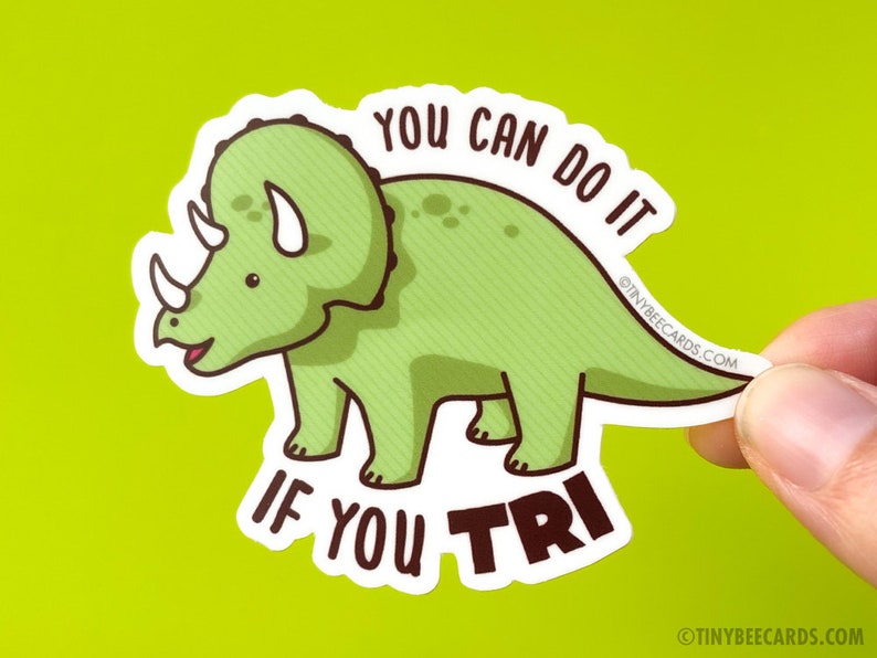 May include: Green cartoon triceratops dinosaur sticker with the text "You can do it if you tri".