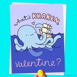 May include: A Valentine's Day card with a blue cartoon octopus holding a ship and the text "what's kraken, valentine?" in pink and purple letters.