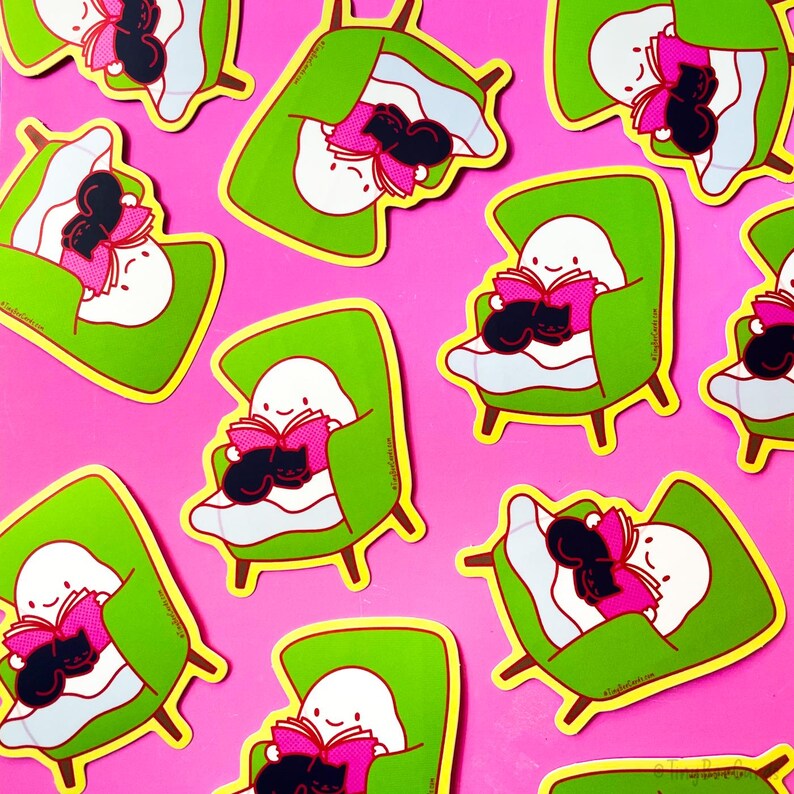 May include: A set of nine stickers featuring a ghost reading a book with a black cat curled up on its lap. The stickers are on a pink background and are in various poses, including sitting in a chair, lying in bed, and reading in a hammock. The stickers are all green and yellow with pink accents.