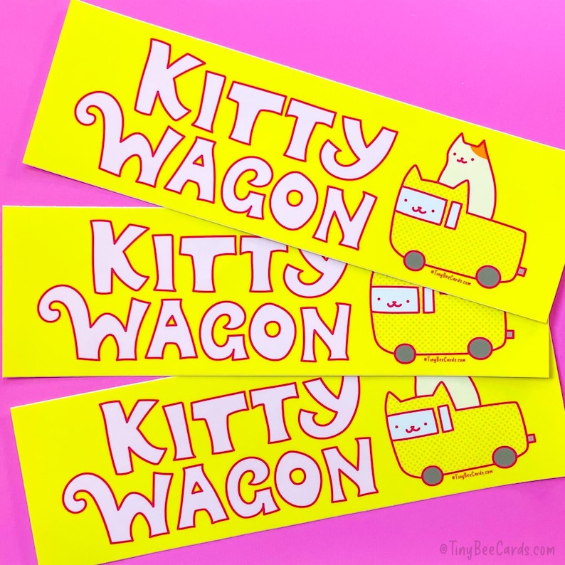 Pode incluir: Tr&ecirc;s autocolantes amarelos com as palavras "KITTY WAGON" numa fonte caprichosa. Cada autocolante apresenta um gato de desenho animado numa carruagem amarela. Os autocolantes est&atilde;o num fundo rosa.