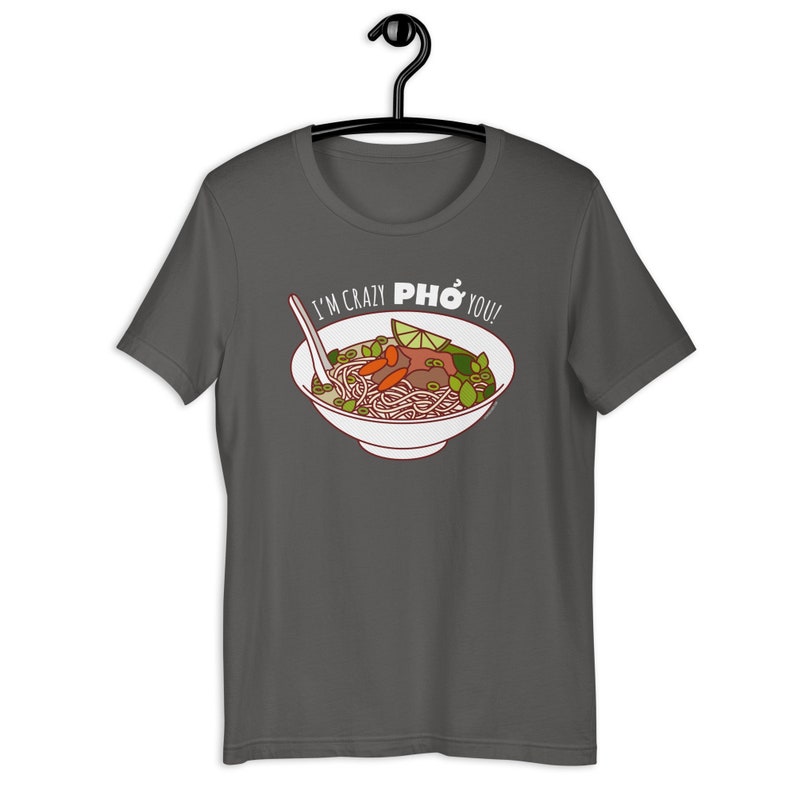 Op de afbeelding: Een donkergrijs T-shirt met een witte afbeelding van een kom pho met de tekst "I'm crazy PHO you!"