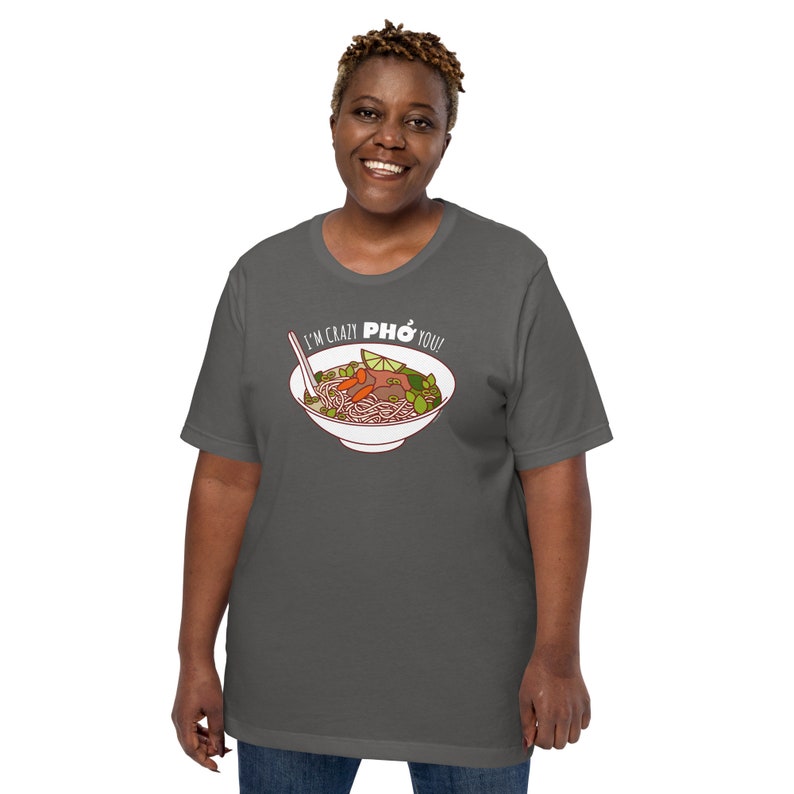 Op de afbeelding: Een donkergrijs T-shirt met een witte afbeelding van een kom pho en de tekst "I'm crazy pho you!"