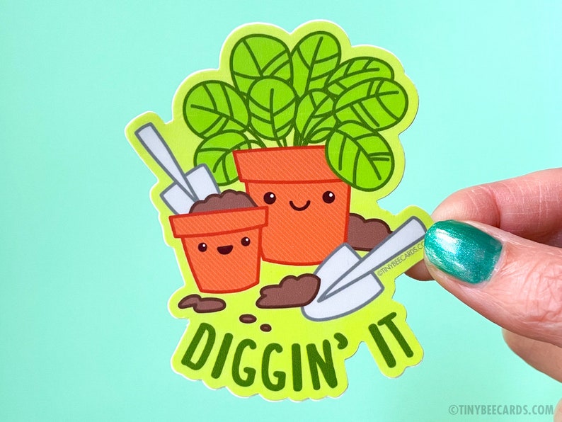 K&ouml;nnte beinhalten: Eine gr&uuml;ne Pflanze in einem Topf mit einem fr&ouml;hlichen Gesicht, ein kleinerer Topf mit einem fr&ouml;hlichen Gesicht und zwei Schaufeln. Der Text "Diggin' It" befindet sich unter den T&ouml;pfen.