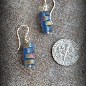 May include: A pair of silver dangle earrings with blue and gold glass beads. The earrings are about the size of a dime.