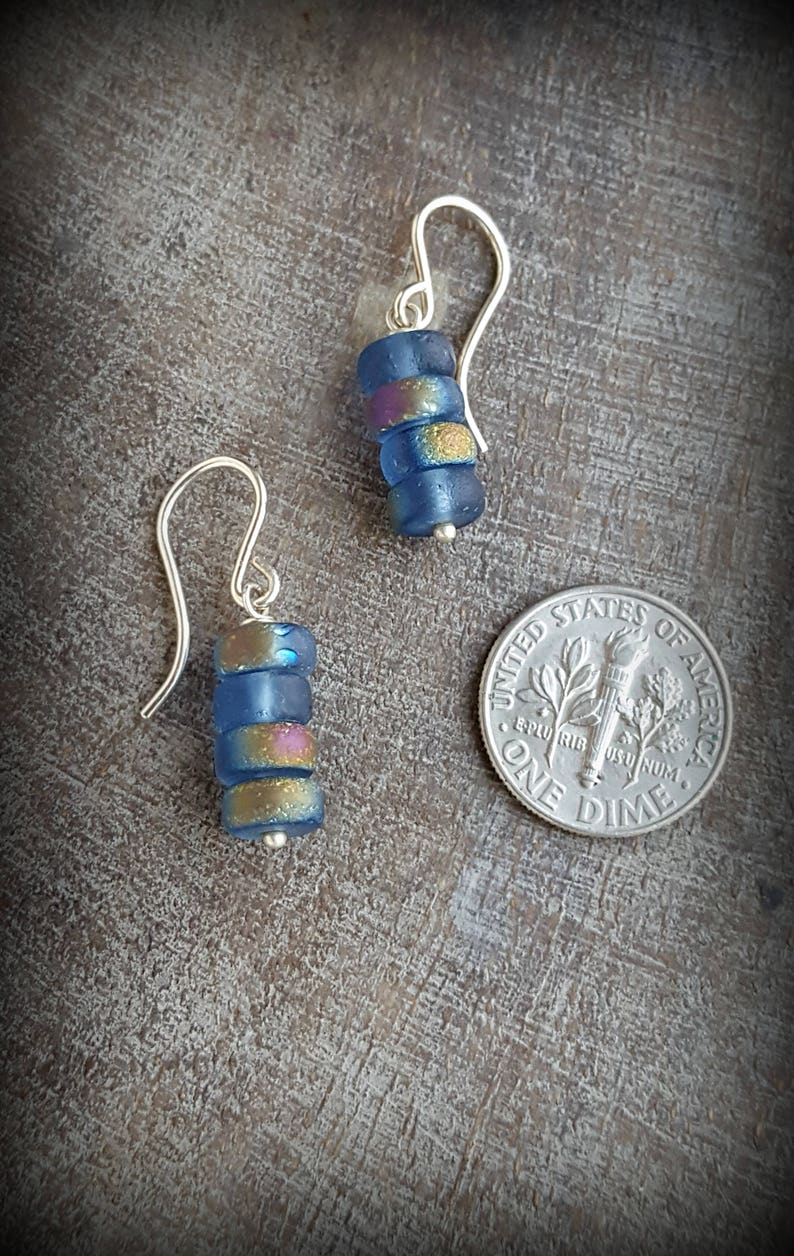 May include: A pair of silver dangle earrings with blue and gold glass beads. The earrings are about the size of a dime.