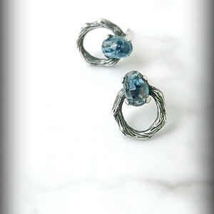Peut inclure: Une paire de boucles d'oreilles en argent avec une pierre pr&eacute;cieuse bleue sertie dans un design de fil torsad&eacute;.