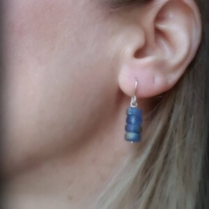May include: A pair of dangle earrings with a silver hook and a stack of blue glass beads.