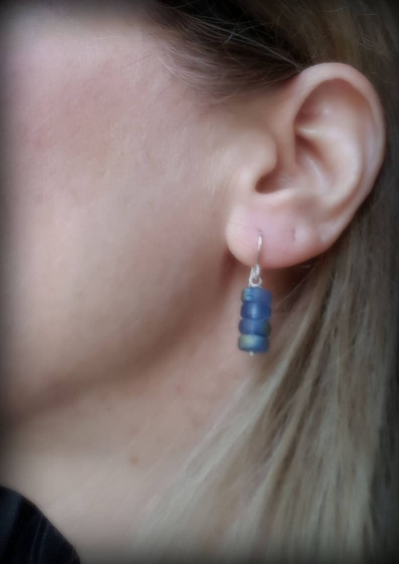 May include: A pair of dangle earrings with a silver hook and a stack of blue glass beads.