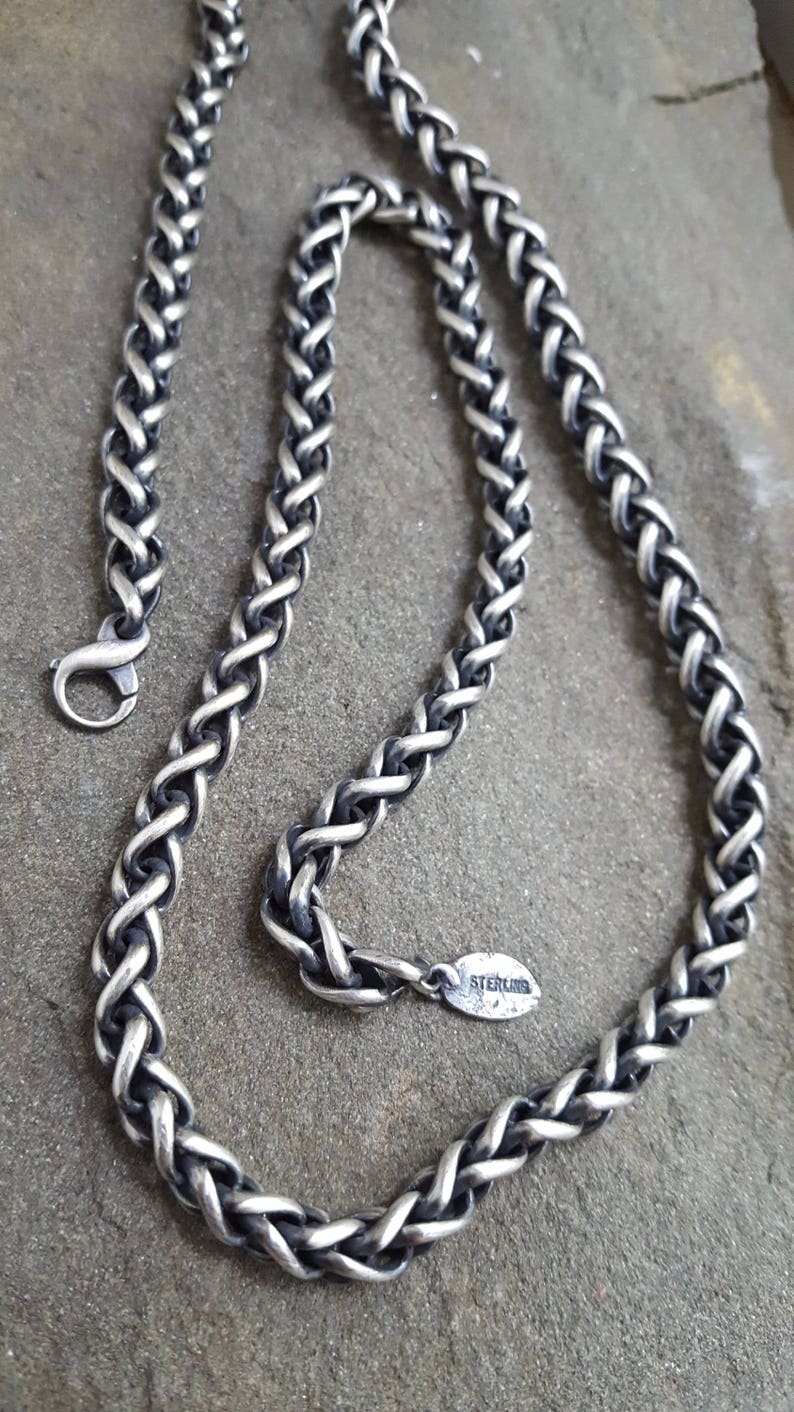 Puede incluir: Un collar de cadena de plata con un dise&ntilde;o trenzado. La cadena tiene un cierre de langosta y una peque&ntilde;a etiqueta ovalada que dice "STERLING".
