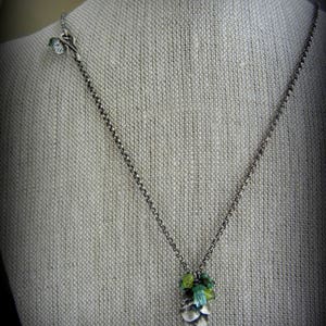 May include: A silver chain necklace with a green and blue gemstone pine cone pendant.