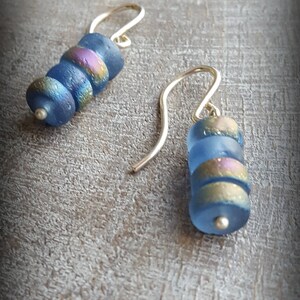 May include: A pair of blue and gold glass bead earrings with silver hooks.
