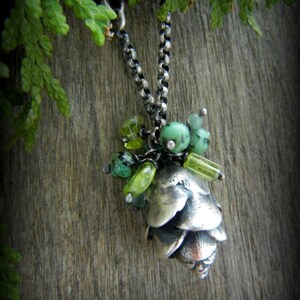 May include: A silver necklace with a pine cone pendant and green gemstone accents.