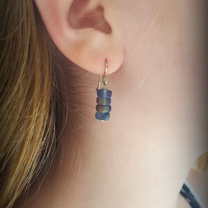 May include: A pair of earrings with a gold hook and a stack of iridescent blue glass beads.