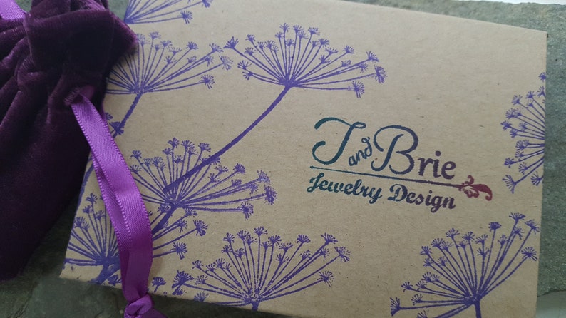 May include: A brown cardboard box with a purple floral design and the text "T and Brie Jewelry Design".