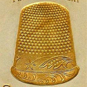 May include: Vintage advertisement for Barker Stiffened Gold Thimbles. The image features a gold thimble with a textured surface and decorative floral and star accents. The text reads "Ask for Barker" and "Man'f'g O's Patent".