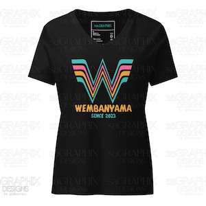 Puede incluir: Camiseta negra con cuello en V con un dise&ntilde;o gr&aacute;fico colorido. El dise&ntilde;o incluye una "W" estilizada en turquesa, rosa y amarillo, con el nombre "WEMBANYAMA" y "SINCE 2023" debajo. Una etiqueta es visible en la esquina superior derecha.