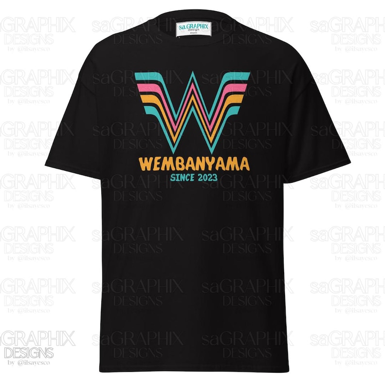 May include: Black t-shirt featuring a colorful "W" graphic with pink, teal, and yellow stripes, above the word "WEMBANYAMA" in yellow, and "SINCE 2023" below. A casual tee for everyday wear.