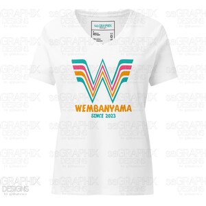 Puede incluir: Camiseta blanca con cuello en V con un dise&ntilde;o gr&aacute;fico colorido. El dise&ntilde;o incluye la palabra "WEMBANYAMA" y el texto "SINCE 2023", utilizando colores turquesa, rosa y naranja. La camiseta tiene una etiqueta que dice "sa.GRAPHIX".