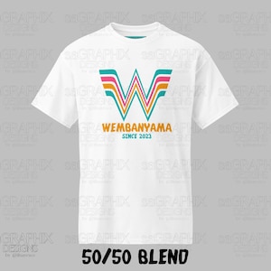 Pu&ograve; includere: Una t-shirt bianca a maniche corte con una grande lettera W stilizzata a strisce color turchese, rosa e arancione. Sotto la lettera, il testo riporta WEMBANYAMA in arancione e SINCE 2023 in turchese. In basso appare il testo 50/50 BLEND.