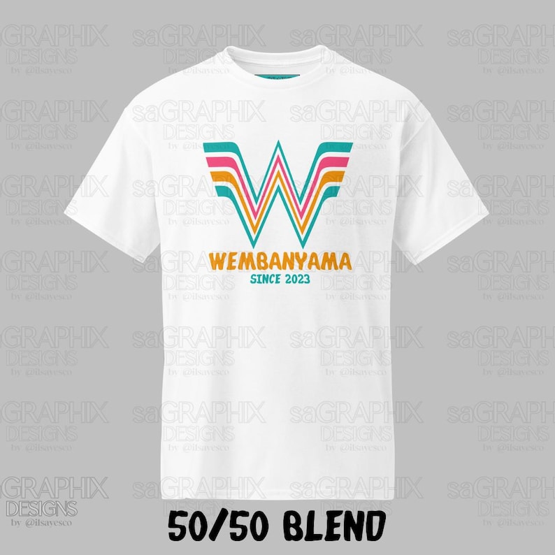Pu&ograve; includere: Una t-shirt bianca a maniche corte con una grande lettera W stilizzata a strisce color turchese, rosa e arancione. Sotto la lettera, il testo riporta WEMBANYAMA in arancione e SINCE 2023 in turchese. In basso appare il testo 50/50 BLEND.