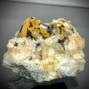 May include: A natural mineral specimen featuring a cluster of quartz crystals with a matrix of black and yellow minerals. The quartz crystals are clear and translucent, while the other minerals have a metallic sheen.