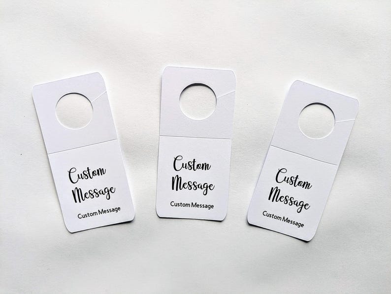 May include: Three white hang tags with a hole at the top. Each tag has the text "Custom Message" printed on it.