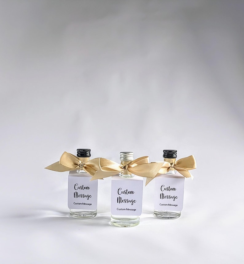 May include: Three small glass bottles with gold ribbon bows and white labels that say "Custom Message".
