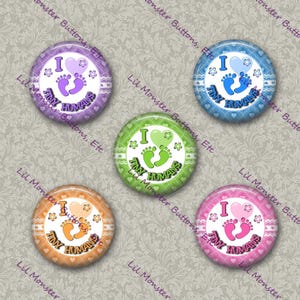 May include: Five circular pinback buttons featuring a white center with a heart, baby footprints, and the text I LOVE TINY HUMANS. Each button has a unique colored border in purple, blue, green, orange, or pink with a matching heart and footprint design.