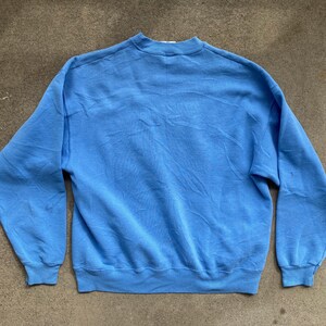 May include: A light blue sweatshirt with long sleeves and a crew neck.