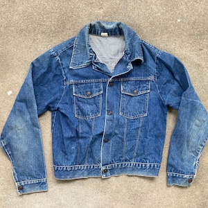 May include: A vintage blue denim jacket with a classic collar, two chest pockets, and button fastenings. The jacket has long sleeves and a slightly faded appearance. The jacket is a standard fit.