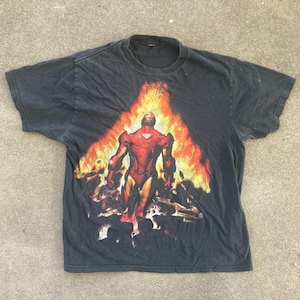 May include: Black t-shirt featuring a graphic of Iron Man in a red and gold suit, standing in front of a fiery background. The shirt is a vintage style.