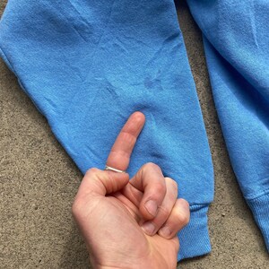 May include: A light blue sweatshirt with long sleeves and a ribbed cuff. The sweatshirt is made of a soft, comfortable fabric.