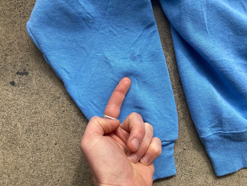 May include: A light blue sweatshirt with long sleeves and a ribbed cuff. The sweatshirt is made of a soft, comfortable fabric.