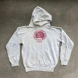 Op de afbeelding: Een lichtgrijze hoodie met een voorzak en een capuchon. De voorkant van de hoodie heeft een cirkelvormig embleem met de tekst "Bartle Scout Reservation" en "R.S.A. Nollivan Staff" in rood en wit.