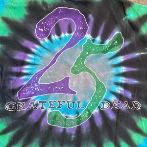 Puede incluir: Una camiseta negra tie-dye con un contorno blanco del n&uacute;mero 23 y las palabras "Grateful Dead" en blanco.