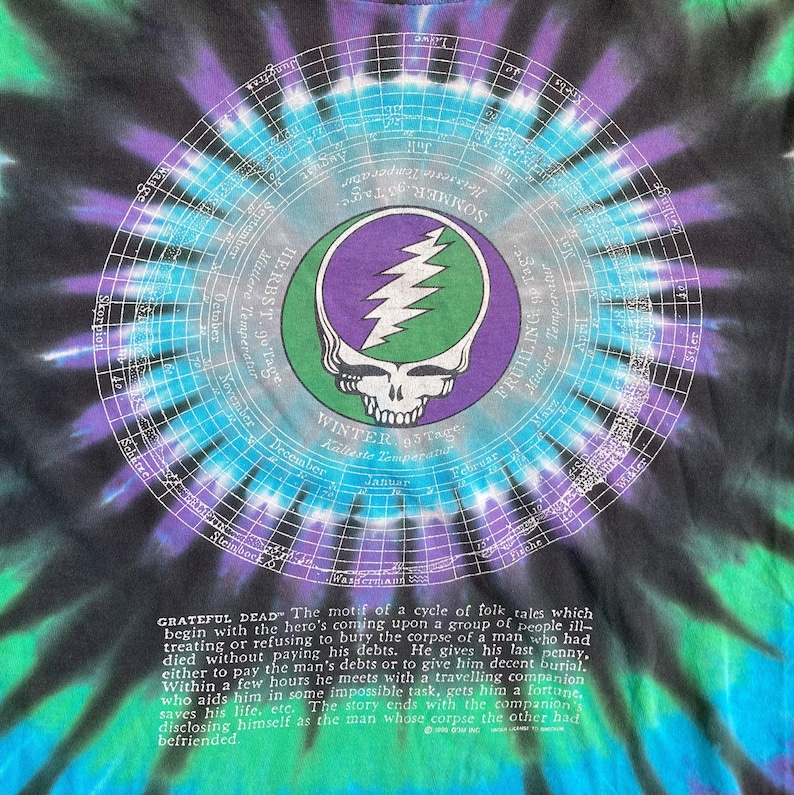 Puede incluir: Una camiseta tie-dye negra, azul y verde con un gr&aacute;fico circular de una calavera con un rayo y el texto "Grateful Dead". El texto "Winter 95 Tage" tambi&eacute;n es visible en la camiseta.