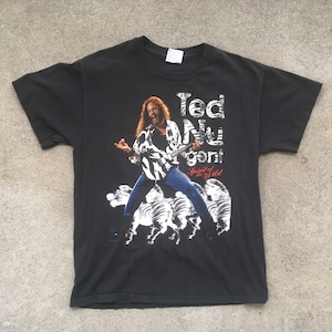 May include: Black t-shirt with a white graphic of Ted Nugent, a musician, playing a guitar. The text "Ted Nugent" and "Spirit of the Wild" are printed on the shirt.