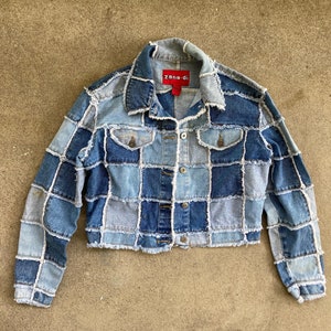 May include: A blue denim jacket with a patchwork design. The jacket has frayed edges and a red "Zara" label on the collar.