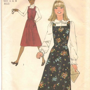 May include: Vintage Simplicity sewing pattern featuring two dress designs. One dress is a solid red jumper, and the other is a black floral print jumper. The pattern includes sizes 6 and 8 for misses.