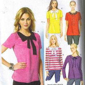 May include: A sewing pattern for a blouse with a bow at the neck. The pattern includes four different styles: a pink blouse with a black bow, a yellow blouse with a white bow, a red blouse with a black bow, and a purple blouse with a black bow. The pattern is for sizes A/B, C, and D.