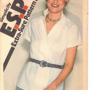 May include: A Simplicity sewing pattern for a white blouse with a collar and short sleeves. The pattern number is 9464 and the price is 95 cents. The pattern is for sizes 10, 12, and 14.