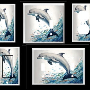 May include: Decorative light switch covers featuring a watercolor painting of a dolphin leaping through blue and green waves. The dolphin is depicted in shades of gray and white, with a dark blue tail. Small orange fish are also visible.