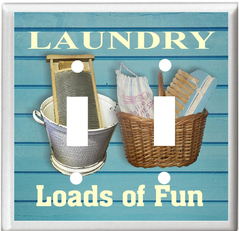 May include: A light blue double light switch cover with the text "Laundry Loads of Fun" in yellow. The switch cover features a vintage washboard, a basket of clothes, and a blue and white laundry bag.