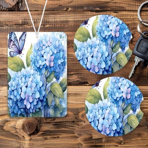 May include: A set of three blue and white hydrangea flower coasters with a butterfly design. The coasters are round and have a white background with green leaves.