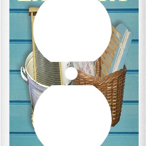 May include: A light blue and white wall outlet cover with a vintage laundry theme. The cover features a white washboard, a wicker basket, and a wooden clothes brush. The text "Laundry Loads of Fun" is printed in yellow on the cover.