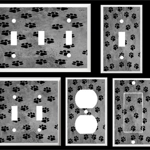 May include: Set of five light switch and outlet covers featuring a black paw print pattern on a gray background.