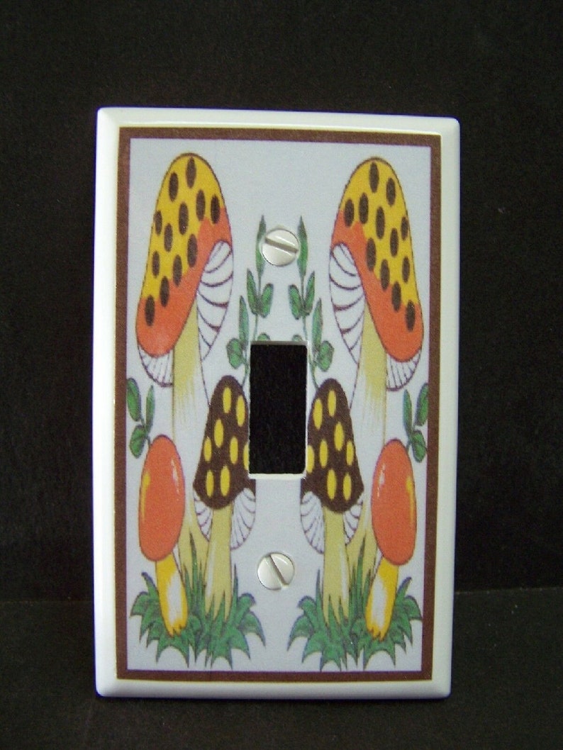 May include: White light switch cover with a brown border and a colorful mushroom design. The mushrooms are red, yellow, brown, and white with black spots.