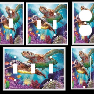 May include: A set of light switch and outlet covers featuring a colorful underwater scene with two sea turtles swimming through coral reefs. The turtles are green, brown, and orange with a blue background.